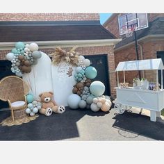 a balloon arch with teddy bears and balloons on it in front of a garage door