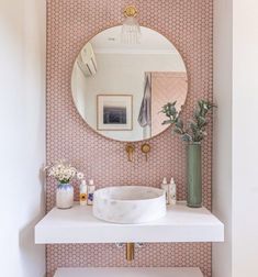 a white sink sitting under a round mirror next to a wall mounted faucet