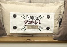 a pillow that says, thank grateful and is sitting on a shelf next to pillows