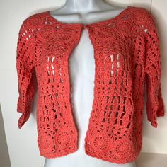 an orange crocheted cardigan on a mannequin