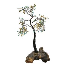 a small bonsai tree with blue beads on it's branches is shown against a white background