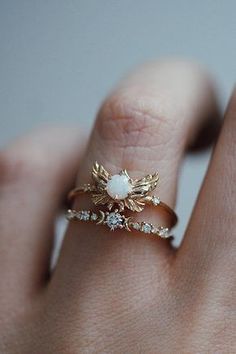 a woman's hand with a gold ring on it and a white stone in the middle