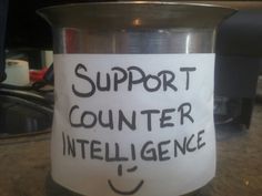 a coffee cup with a sign on it that says support counter inteliligence