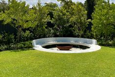 an outdoor fire pit surrounded by grass and trees