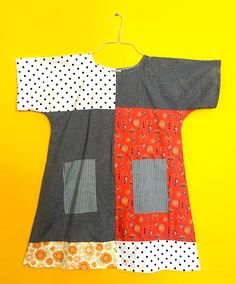 a piece of clothing is hanging on a yellow background with polka dots and oranges