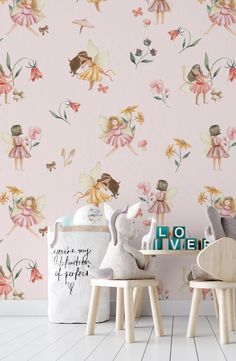 two small wooden stools in front of a pink wallpapered with fairy images