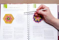 a person is holding a pencil and crocheting on an open page of a book