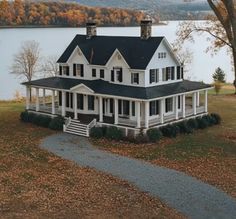 a large white house sitting on top of a lush green field next to a lake