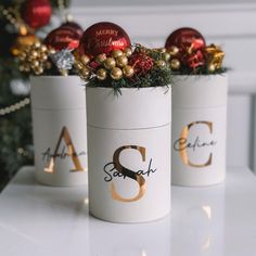 three christmas decorations are sitting in white containers