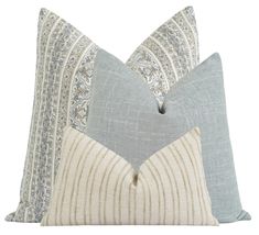 two pillows with decorative designs on them, one in grey and the other in white