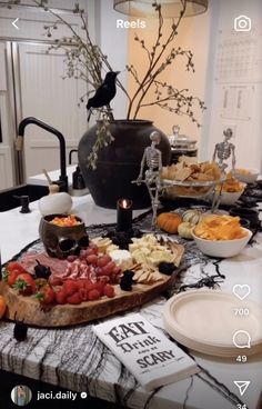 a table topped with lots of food next to a black vase filled with fruit and veggies