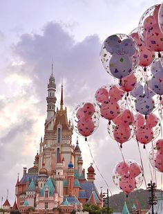 many balloons floating in the air near a castle