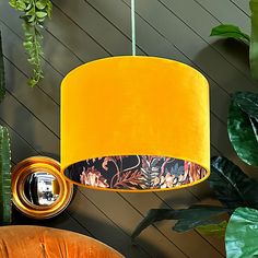 a yellow lamp hanging from a ceiling next to plants