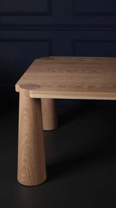 a wooden table sitting on top of a black floor in front of a blue wall