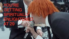 a man with red hair is singing into a microphone and has the caption you're getting virtually enlightened at 29