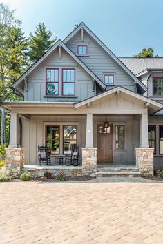 the front view of a house with stone pillars and brick walkway leading up to it