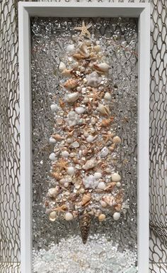 a christmas tree made out of seashells in a white frame on the wall