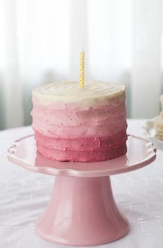 a pink and white cake with a single candle on top