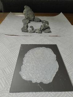 some rocks are sitting on top of a white table cloth and there is a rock in the middle