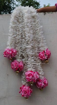 pink flowers are hanging from the side of a wall