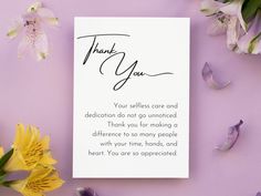 a thank you card sitting on top of a purple table next to flowers and petals