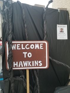 a welcome to hawks sign in front of black tarps