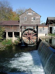 an old mill and water wheel on the side of a river