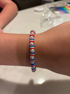 a woman's arm with a bracelet made out of glass beads and red white and blue beads