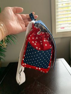 a hand is holding a small bag with red, white and blue fabric on it