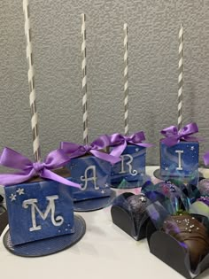 there are chocolates and candy wrapped in blue paper with purple ribbons on the table