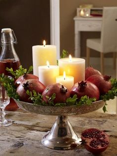 a table topped with candles and pomegranates