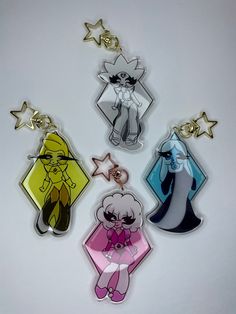 four key chains with cartoon characters hanging from the top one is white and has gold stars on it