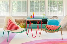 two chairs and a table in front of a window with colorful rugs on the floor