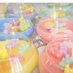 there are many different colored candles in the glass bowls on the table, and one is filled with small candies