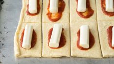 several pieces of bread with cheese and sauce on them sitting on a baking sheet, ready to go into the oven