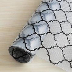 a white and black patterned wallpaper on a wooden table with a roll of wrapping paper