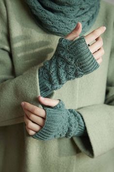 a woman wearing green knitted fingerless mittens and a scarf around her neck