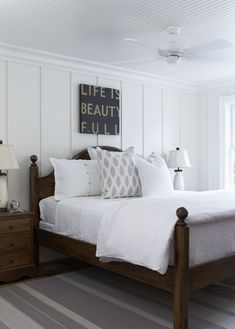 a bed with white sheets and pillows in a bedroom