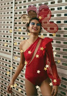 a woman in a red bodysuit with gold stars on her head and one arm