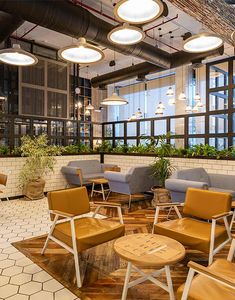 an office lobby with chairs, tables and potted plants