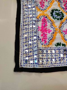 a piece of cloth with beads and sequins on the edges is laying on a white surface