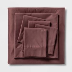 four folded sheets and two pillow cases on top of each other, in maroon color