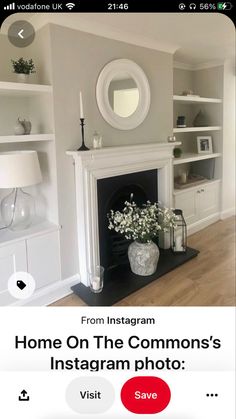 a living room with a fire place and white shelves on the wall next to it