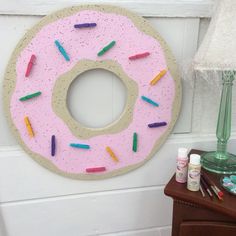 a pink doughnut with sprinkles hanging on the wall next to a lamp