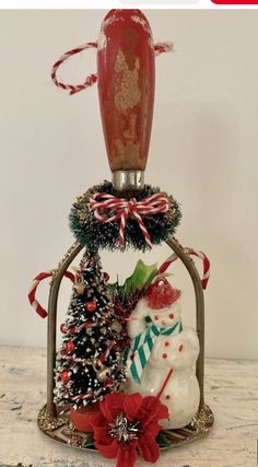 a snowman and christmas tree in a glass bell jar with red ribbon on top