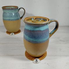 two blue and brown pottery pitchers sitting next to each other