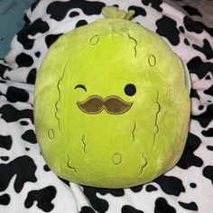 a green stuffed animal with a mustache and moustache on it's face