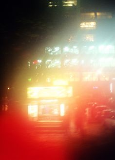 blurry image of city bus at night time with lights on the top and bottom