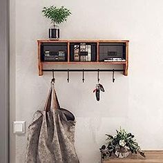 a coat rack with two coats hanging from it's sides and a potted plant on the other side