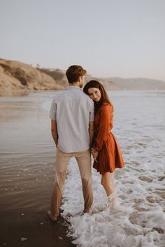 a man and woman are standing in the water at the beach